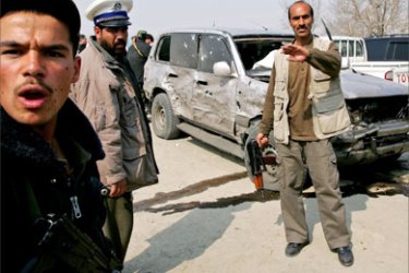 Afghan security personnel guard a vehicle belonging to former Afghan president Sibghatullah Mojadidi, which was damaged in a suicide car bomb attack in Kabul March 12, 2006.