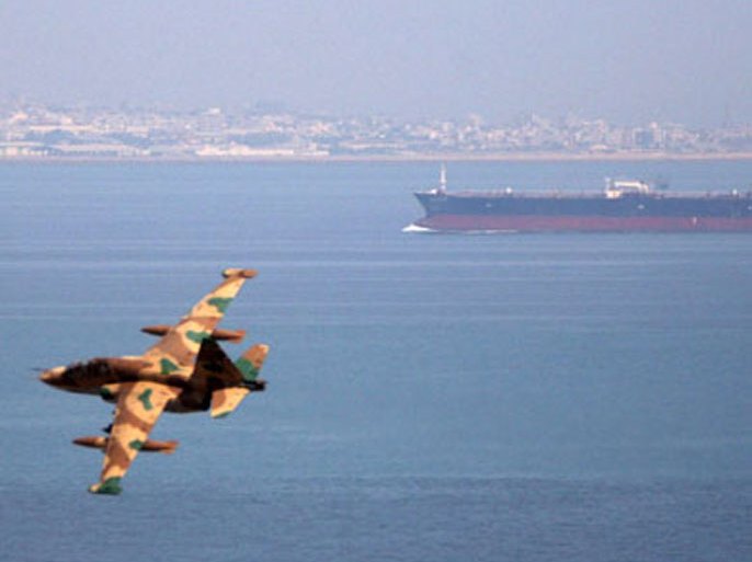 An Iranian military fighter plane flies past an oil tanker during naval manoeuvres in the Persian Gulf and Sea of Oman