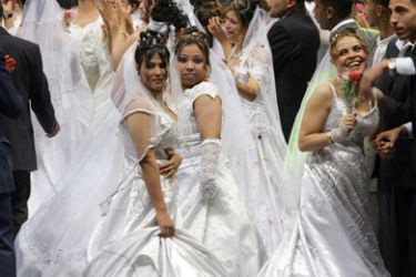 Newly wed brides celebrate on a stand in an indoor facility of the Cairo International Stadium 06 April 2006. The mass wedding of some 500 couples, including Muslims and Copts,