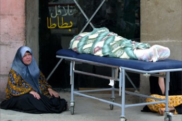An Iraqi woman sits at a local hospital beside the corpse of a relative killed in a car bomb attack in Baghdad, 07 May 2006. A total of 69 people were reported killed across Iraq today in car bombings and execution-style sectarian killings, reinforcing fears the country remains on the brink of civil war as it seeks to finalize a new government.