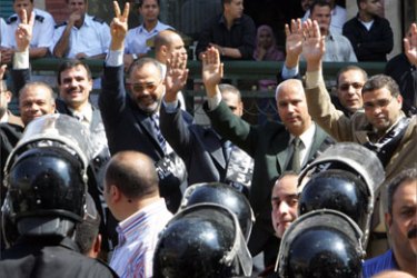 Members of the Egyptian opposition group the Muslim Brotherhood and parliament deputies flash victory signs to riot police outside the Egyptian Supreme Court in Cairo, 18 May 2006, before a hearing in the case of two pro-reform judges who face disciplinary action for allegedly bringing the judiciary into disrepute for accusing some of their colleagues of helping to rig last year's parliamentary polls.