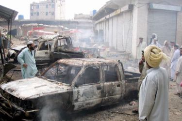 Pakistani tribesmen look at burned vehicles hit by Pakistani security forces in Miranshah, the main town in North Waziristan, June 4, 2006.