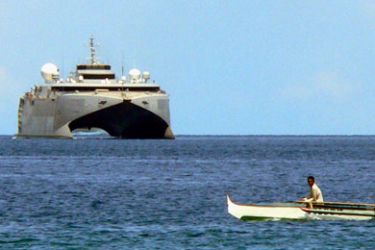 A fishing boat passes the US High Speed Vessel (HSV-X1) Joint Venture anchored in Sulu sea off Jolo island 22 June 2006. The modern catamaran ferry transported medical