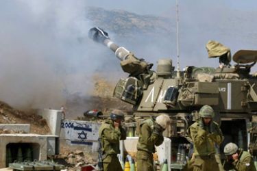 Israeli soldiers stand by a mobile artillery piece firing across the Lebanese frontier July 12, 2006.