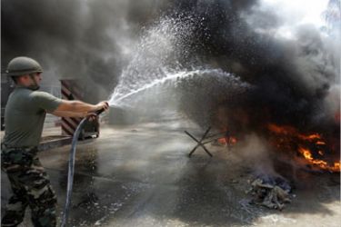 afp - A Lebanese soldier army tries to extinguish a burning cicilian car following an Israeli air raid in the southern city of Tyre 23 July 2006