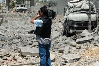 A journalist films the damage in the rubble of buildings, destroyed in an Israeli airstrikes, 28 July 2006 in Shoukine, outside Nabatiyeh. Five civilians, including a Jordanian,