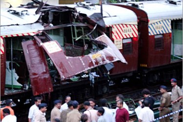 REUTERS/ Security officials gather near a damaged local train compartment hit by a blast in Mumbai, formerly known as Bombay, July 11, 2006. More than 100 people were killed on