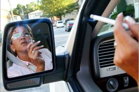 REUTERS /A woman is reflected on a car mirror smoking a cigarette in New York in this September 21, 2004 file photo. Cigarette makers escaped major financial penalties on August 17, 2006