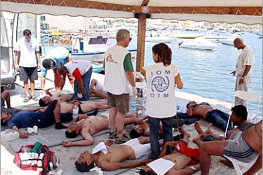 AFP / International Organization of Migration (IOM) and Medecins sans frontieres (Doctors Without Borders) workers give first aid to would be illegal immigrants at the port of Lampedusa,