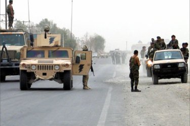 Afghan and foreign troops keep watch after an attack in Kandahar August 17, 2006. A suicide bomber blew himself up near an Afghan police post on Thursday, killing himself and wounding seven police in the volatile southern province of Uruzgan, the provincial police chief said.