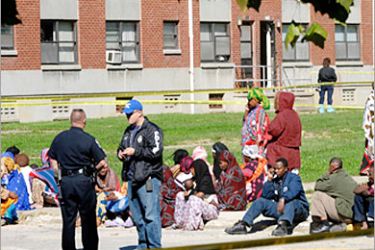REUTERS /Somalian immigrants wait in a taped-off area to talk to police after the bodies of four young children were found at their Iroquois Housing projects apartment (behind) in Louisville,