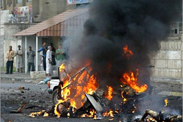 AFP / Black smoke rises from burning corpses lying on the ground in the street next to the wreckage of a car bomb in central Baghdad, 31 October 2006. A car bomb exploded in central