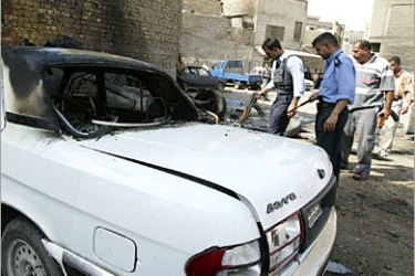 REUTERS/ Police officers inspect the scene after bomb attacks at a parking lot in Baghdad October 12, 2006. Five people were killed and 10 were wounded, including four police officers,