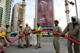 . AFP / An advertisement for the 15th Asian Games towers over workers in Doha, 28 November 2006, three days before the opening ceremony of the games. More than 13,000 athletes