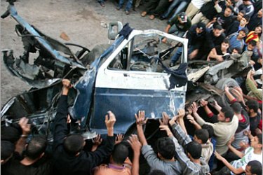 AFP/ Palestinians gather around a destroyed vehicle following an Israeli missile attack in Gaza City, 04 November 2006. A member of the armed wing of the radical Islamist movement