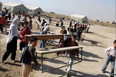 f_Afghan students carry benches at a school in Kabul, 25 November 2006. Nearly five million Afghan children, more than half of them girls, have returend to schools following