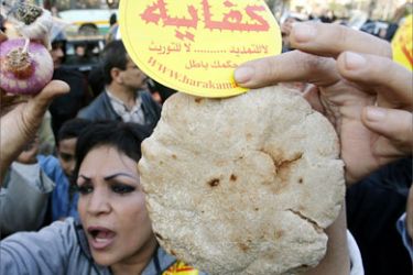 (FILES) An Egyptian supporter of the Kefaya movement holds up a loaf of bread and an onion during a protest in front of the Sayyeda Zeinab Mosque in Cairo, 18 January 2007