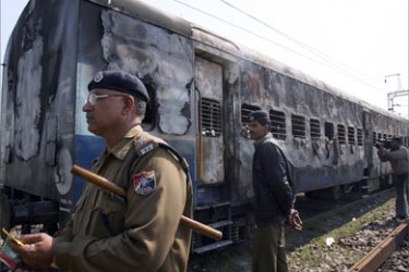 A Railway Protection Police (RPF) personnel stands guard beside the charred carriages of the blasts-hit "Samjhauta (Friendship) Express" train, at the Deewana railway station near Panipat in Haryana some 100 km north of New Delhi, 19 February 2007