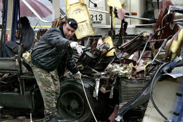 A Lebanese soldier gestures as he takes evidence from one of the two buses that tore when two bombs exploded on board in the village of Ain Alak, northeast of Beirut, 13 February 2007