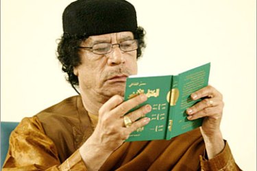 REUTERS /Libyan leader Muammar Gaddafi reads a green book during his debate on democracy with two Western scholars in the desert in Sebha March 2, 2007, in a move apparently designed to further the resumption of international ties following years of isolation. Speaking on the 30th anniversary of his declaration of a Jamahiriyah or state of the masses,