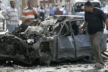r_A resident looks at a burnt vehicle after a car bomb attack in Baghdad April 15, 2007. The attack which targeted a police patrol killed five people and wounded 10