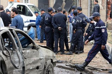 AFP/Algerian policemen pass by a damaged car in front of the Government Palace in the center of Algiers City 11 April 2007. At least 17 people were killed and scores injured in a series of car bombs that rocked the Algerian capital