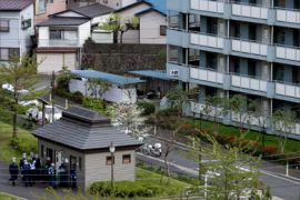 Policemen gather against a small house to watch an apartment in Machida city, suburban Tokyo, 20 April 2007