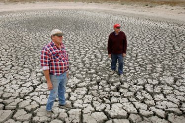 In this file picture taken 14 November 2006, Farmer Marshall Rodda (L) and farmhand Gilbert Fryatt (R) inspect an empty dam, leaving him with fields of stunted wheat stalks, normally thigh high, and which have only managed only a few inches growth in the parched earth of the Australian wheat belt area of Wimmera, northwest of Melbourne.