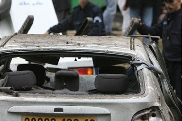 AFP/Algerian policemen inspect a damaged car after a suicide car bomb exploded near the Government Palace in the centre of Algiers 11 April 2007. Several explosions hit the Algerian capital,