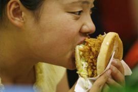 A woman eats a burger at a fast food restaurent in Beijing, 10 July 2007. A "western" diet heavy on red meat, starches and sweets is linked to a rise in breast cancer among post-menopausal Chinese woman
