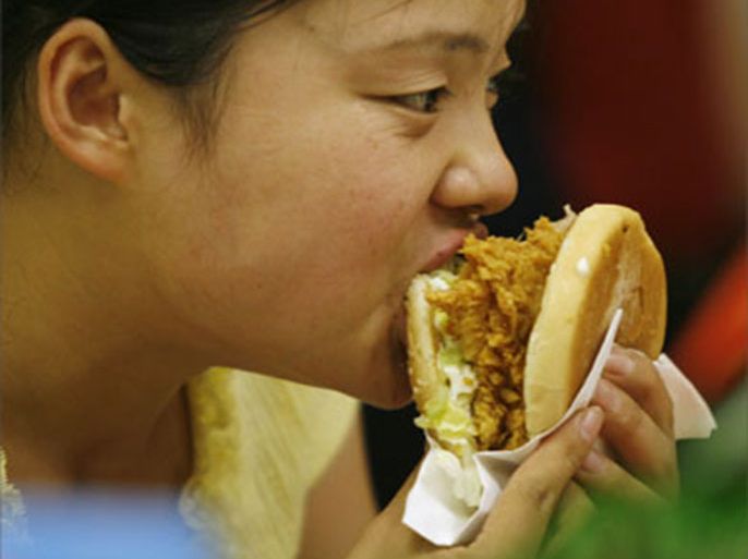 A woman eats a burger at a fast food restaurent in Beijing, 10 July 2007. A "western" diet heavy on red meat, starches and sweets is linked to a rise in breast cancer among post-menopausal Chinese woman
