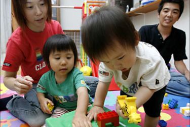 r_Tomoyo Suzuki and her husband play with their adopted children at their home near Tokyo July 4, 2007. When a newborn baby girl was left in Japan's controversial
