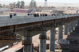 People walk along a bridge during an opening ceremony in Nizhny Panj at the Afghan-Tajik border, 26 August 2007. A road bridge linking Tajikistan and Afghanistan paid