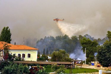 AFP/ A firefighting plane spills water to extinguish fire burning in the town of Ancient Olympia 26 August 2007. The death toll from Greece's fires rose to 57 following the discovery of another body in the Peloponnese peninsula, the firefighting service said late today.