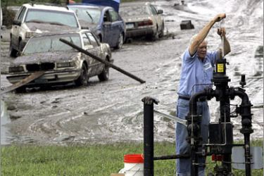 REUTERS/Dan Fitch of Minnesota Energy Resources repairs a natural gas pressure regulating station by the flooded Rush Creek levee and mud sodden cars in Rushford