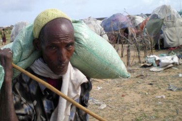 A displaced Somali man carries relief food from a distribution centre in the port city of Kismayu, August 30, 2007. A Somali reconciliation conference seen by many as the best hope