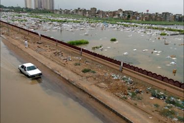 f_Pakistani commuters ride past a submerged graveyard in Karachi, 11 August 2007. Flooding caused by torrential rains has killed at least 22 people in Pakistan's southern port city