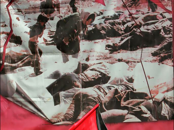 af p : A Palestinian boy waves his national flag in front of a poster showing images of the 1982 Sabra and Shatila massacre during a ceremony to mark the 25th anniversary of