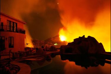 f/Smoke and flames are reflected a swimming pool behind a hilltop home that was nearly destroyed before dawn in Lyons Valley as the Harris Fire continues growing beyond 70,000 acres 24 October 2007 near Jamul,