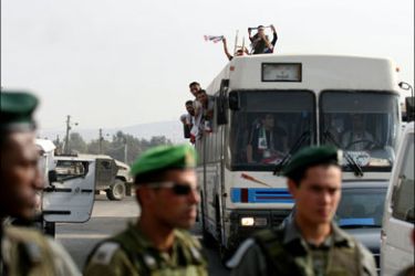 afp : Israeli soldiers stand guard as released Palestinian prisoners cross with a bus the Ofer checkpoint, near the West Bank city of Ramallah, 01 October 2007. Fifty-seven