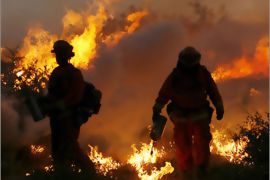 REUTERS/California Department of Forestry fire fighters Alex Carter (L) and Javier Gasga set a burn out as they battle the Witch Fire near Pauma Valley, California,