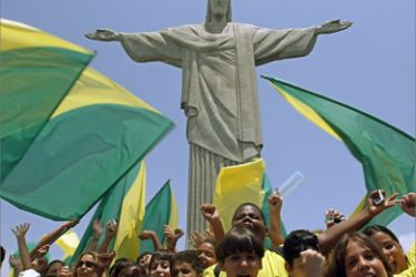 Brazilian schoolboys wave flags and cheer in front of the statue to Christ the Redeemer 30 October, 2007 in Rio de Janeiro, Brazil