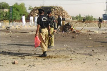 afp : Pakistani policemen inspect the site of a suicide attack on the outskirts of Bannu, 01 October 2007. A suicide bomber disguised in a woman's burqa blew himself up at a