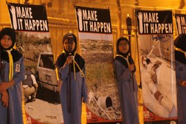 Girl scouts hold torches as they stand near posters of cluster bombs victims to mark the Global Day of Action Against Cluster Bombs, during a sit-in held in front of the parliament in Beirut November 5, 2007-ر