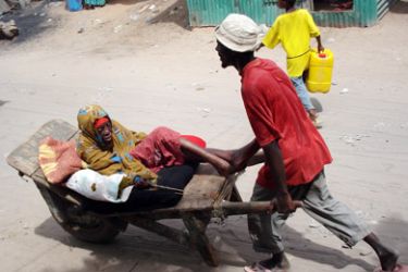 A Somali woman is carried in a wheelbarrow as she reportedly leaves her neighborhood in an effort to flee from fighting in Mogadishu, Somalia,
