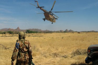 ف-A chadian soldier watches a Chadian military MI17 troop transport helicopter, transformed into a helicopter bomber, fly over 06 December 2007