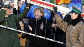 German Chancellor Angela Merkel (C) and European Commission President Jose Manuel Barroso (R) smile as Polish border police and German federal police lift up