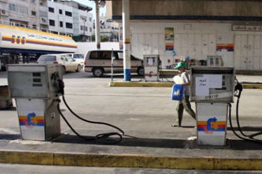 AFP/ A sign pinned on a petrol pump in Arabic reads "No Fuel" as a Palestinian boy walks across the empty forecourt of a petrol station with empty jerry cans due to fuel shortages in Gaza City, 02 December 2007.