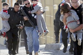 REUTERS/ Police officers carry children away during a gun battle in Tijuana, in Mexico's state of Baja California, January 17, 2008. A shootout on Thursday, after police agents moved in on a