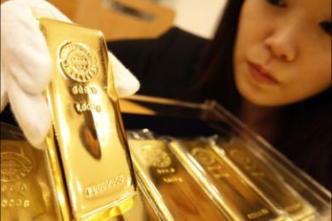 r - An employee of Tanaka Kikinzoku Jewerly K.K. displays a gold bar at the company's store in Tokyo January 29, 2008. Gold and platinum hit historic highs for a third straight